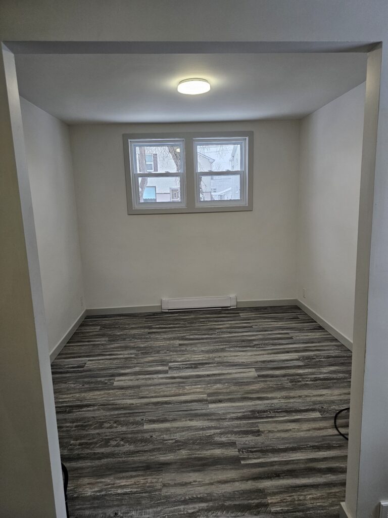 Completed room renovation with modern vinyl plank flooring and fresh paint